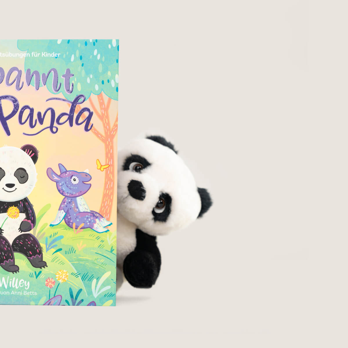 Ein Bukowski Schweden Panda Plüsch lugt hinter einem farbenfrohen Kinderbuch hervor, das einen illustrierten Panda und einen lilafarbenen Dinosaurier auf dem Einband zeigt, vor einem schlichten hellen Hintergrund.